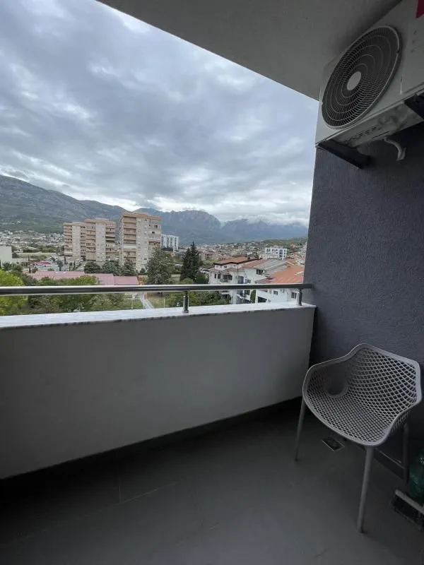 Small furnished balcony with a view of the city and mountains.
