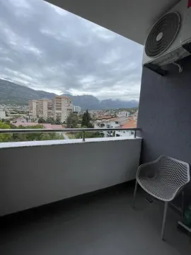 Small furnished balcony with a view of the city and mountains. - image 9