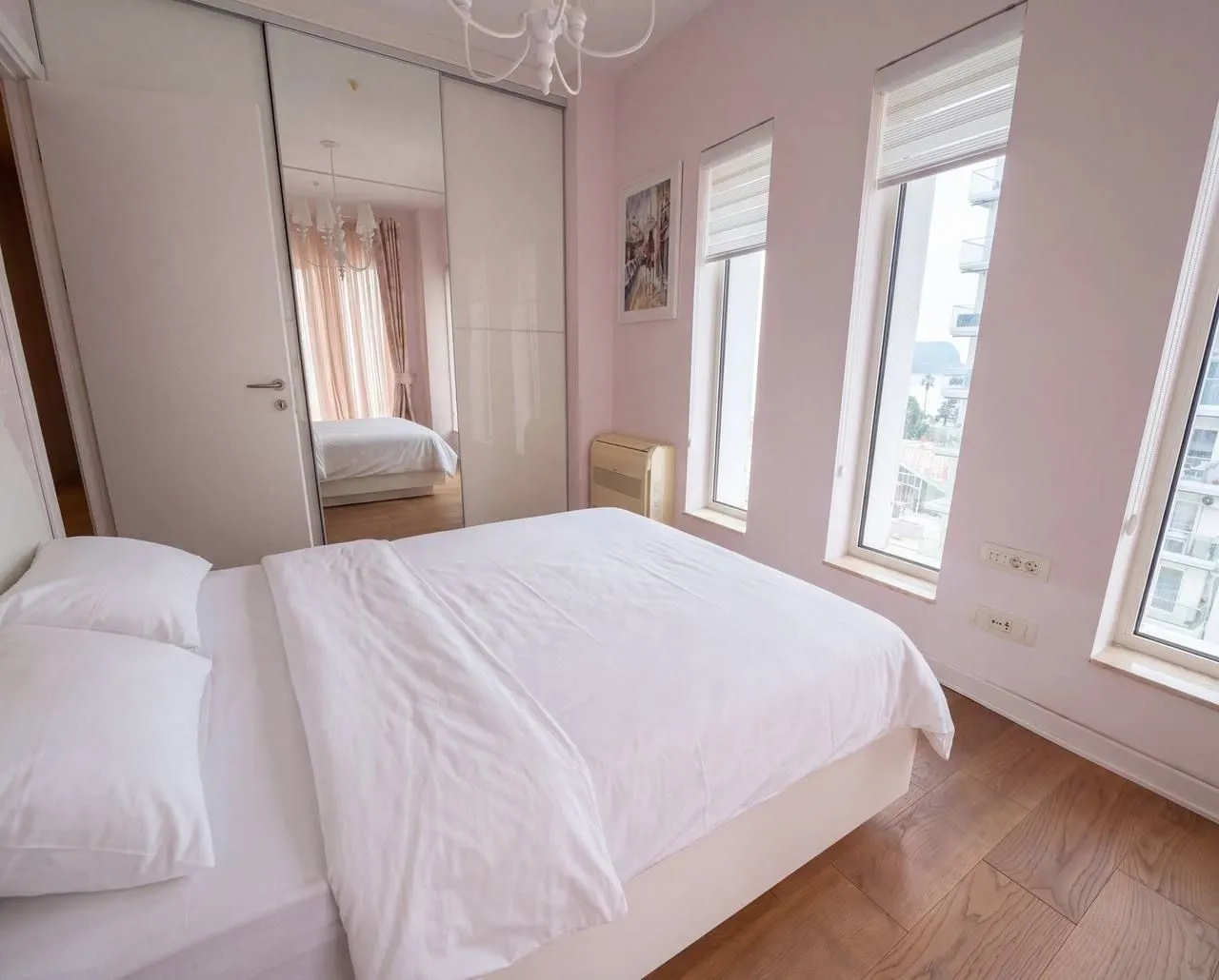 Bright bedroom with a large double bed and a mirrored wardrobe.