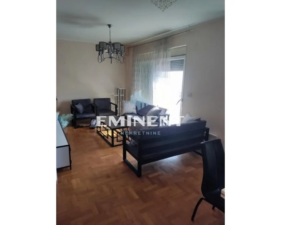 Living room with seating furniture and parquet flooring.