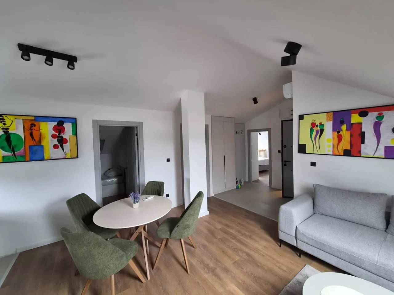 Living room with a dining area, sofa, and artworks on the walls.