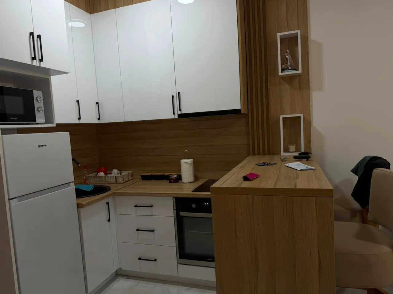Modern kitchen with white cabinets, wooden accents, and built-in appliances.