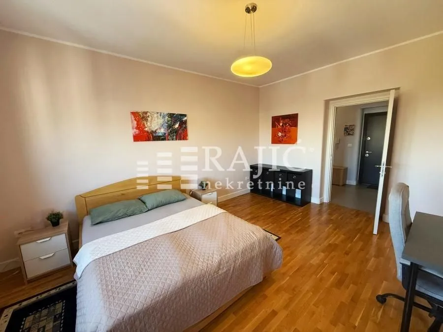 Furnished bedroom with a double bed, desk, and hardwood flooring.
