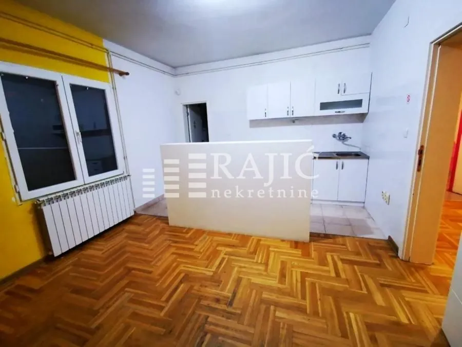 Empty kitchen with wooden floor and white cabinets.
