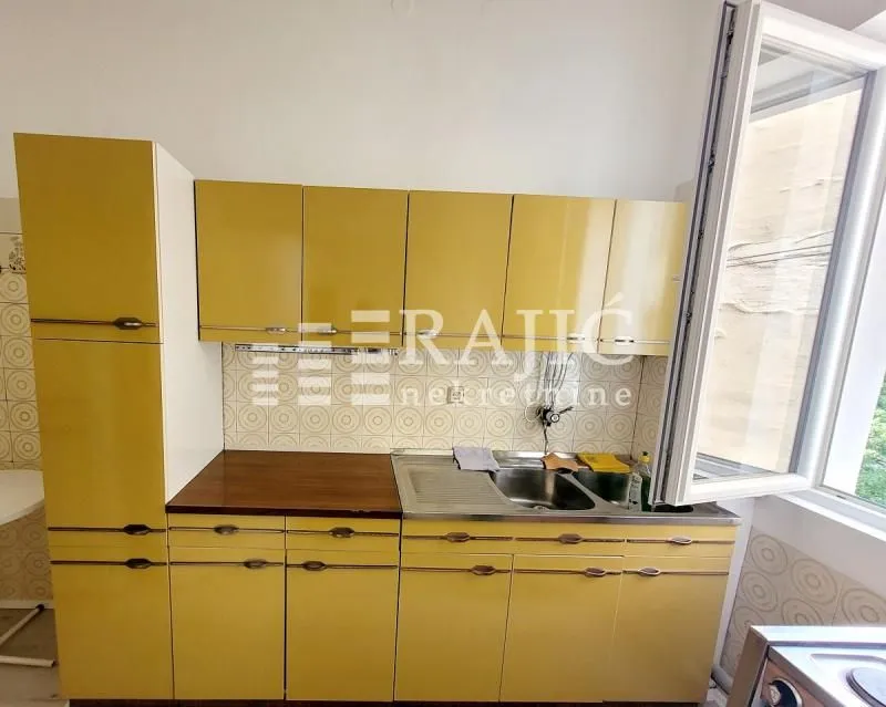 Small kitchen with yellow cabinets and a sink.