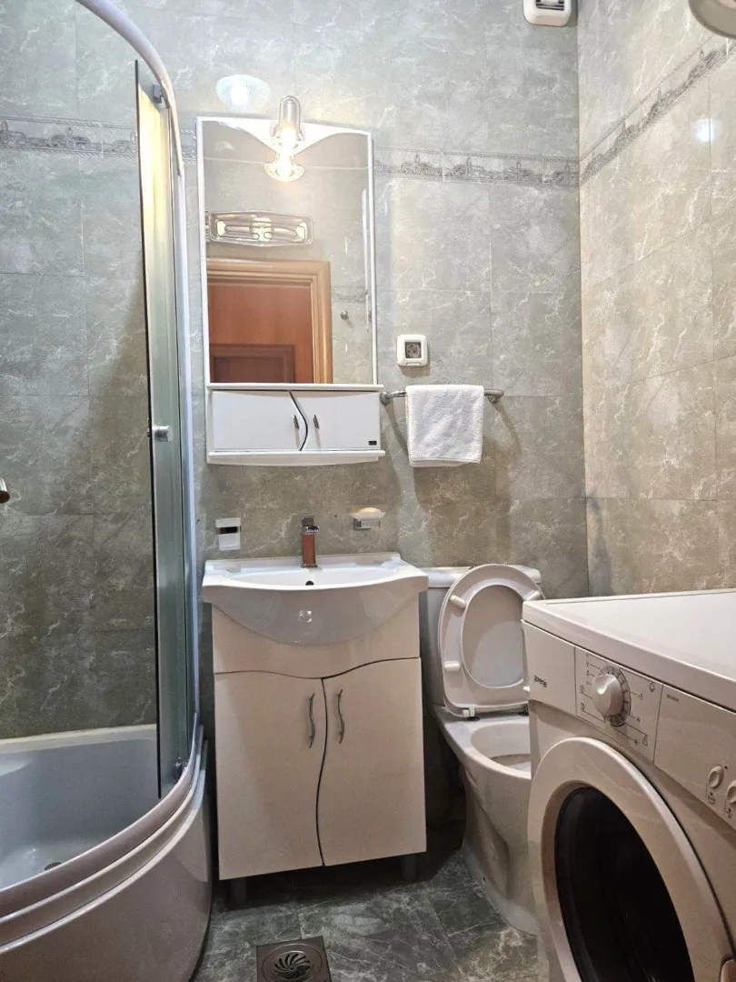 Bathroom equipped with a shower cabin, washbasin, toilet, and washing machine.