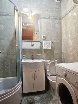 Bathroom equipped with a shower cabin, washbasin, toilet, and washing machine. - image 5