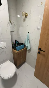 Small bathroom lined with marble tiles featuring a washbasin and a toilet. - image 4