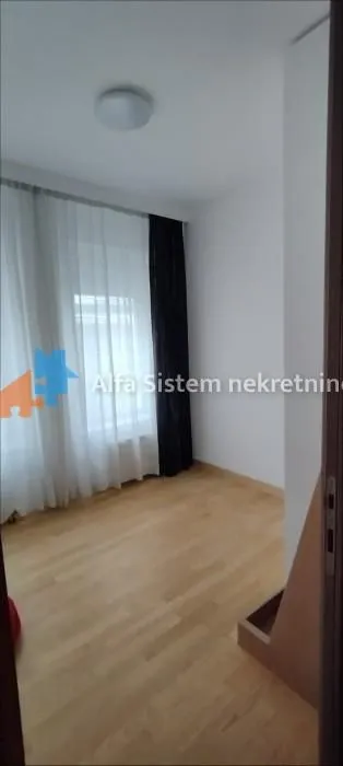 Prazna soba sa drvenim podom i prozorom sa zavesama.