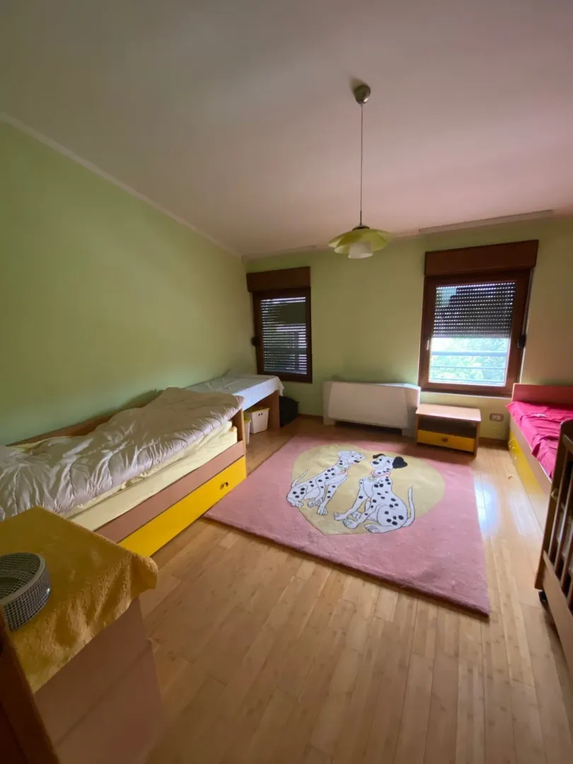 Dječija soba sa dva kreveta i šarenim tepihom.