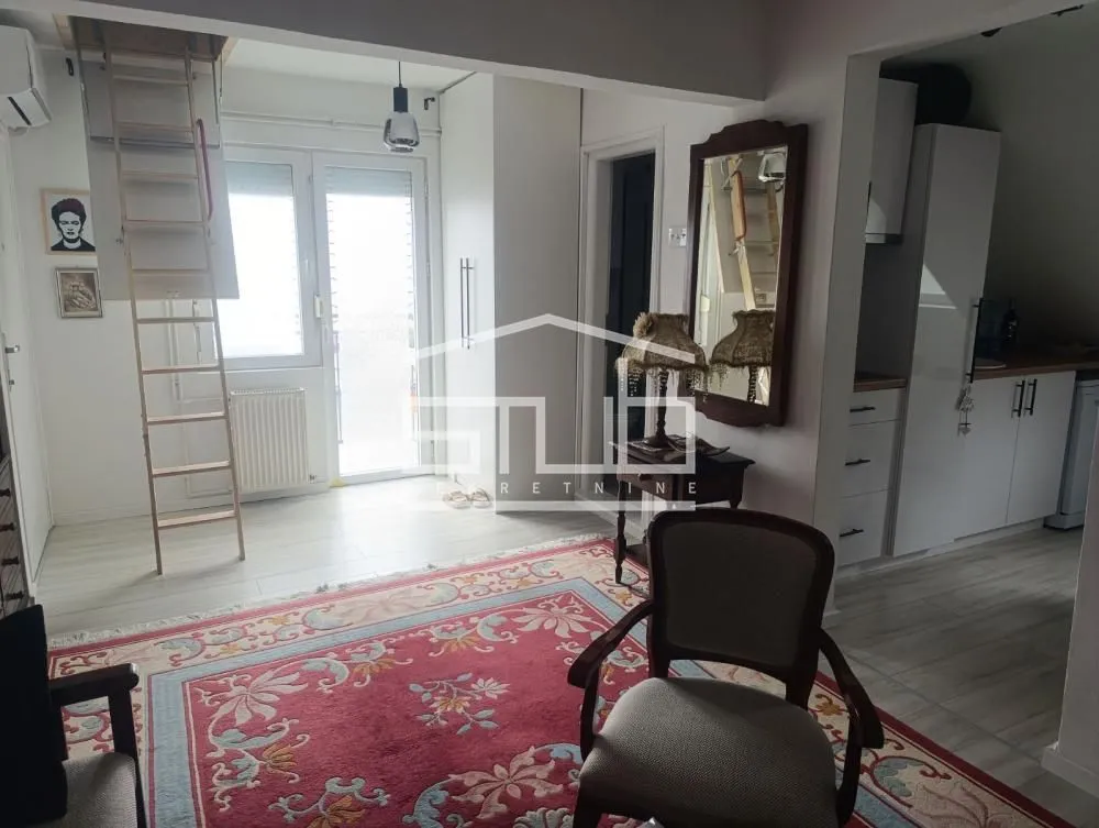 Living room with a table, rug, and stairs leading to the gallery.