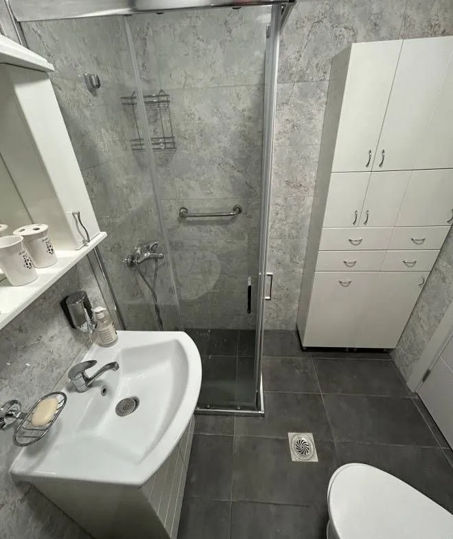 Bathroom with a shower cabin, washbasin, and white cabinet.