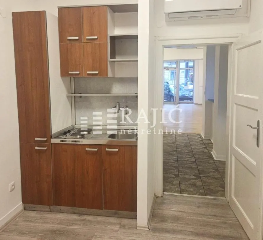 Small wooden kitchen within the apartment with a sink and cabinets.
