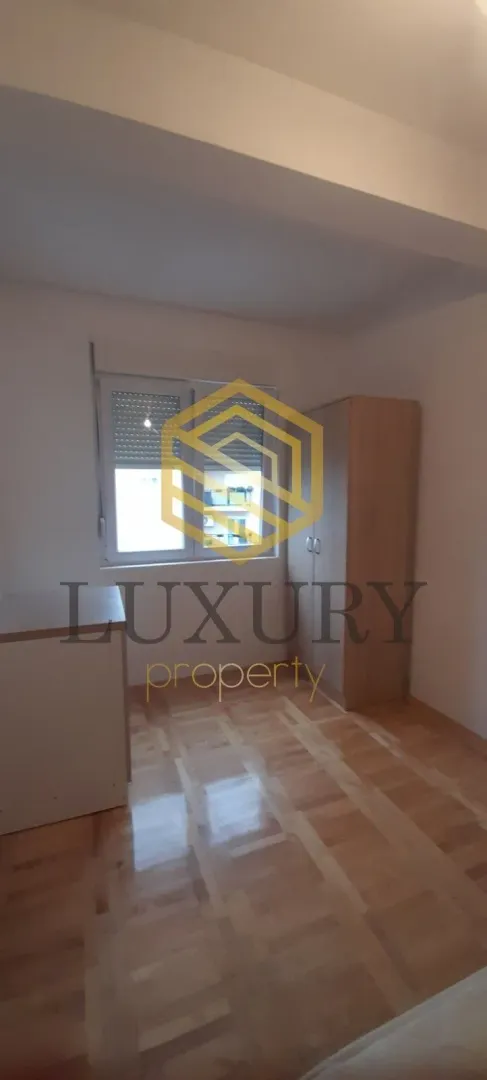 Empty bedroom with parquet flooring, window, and a wardrobe.