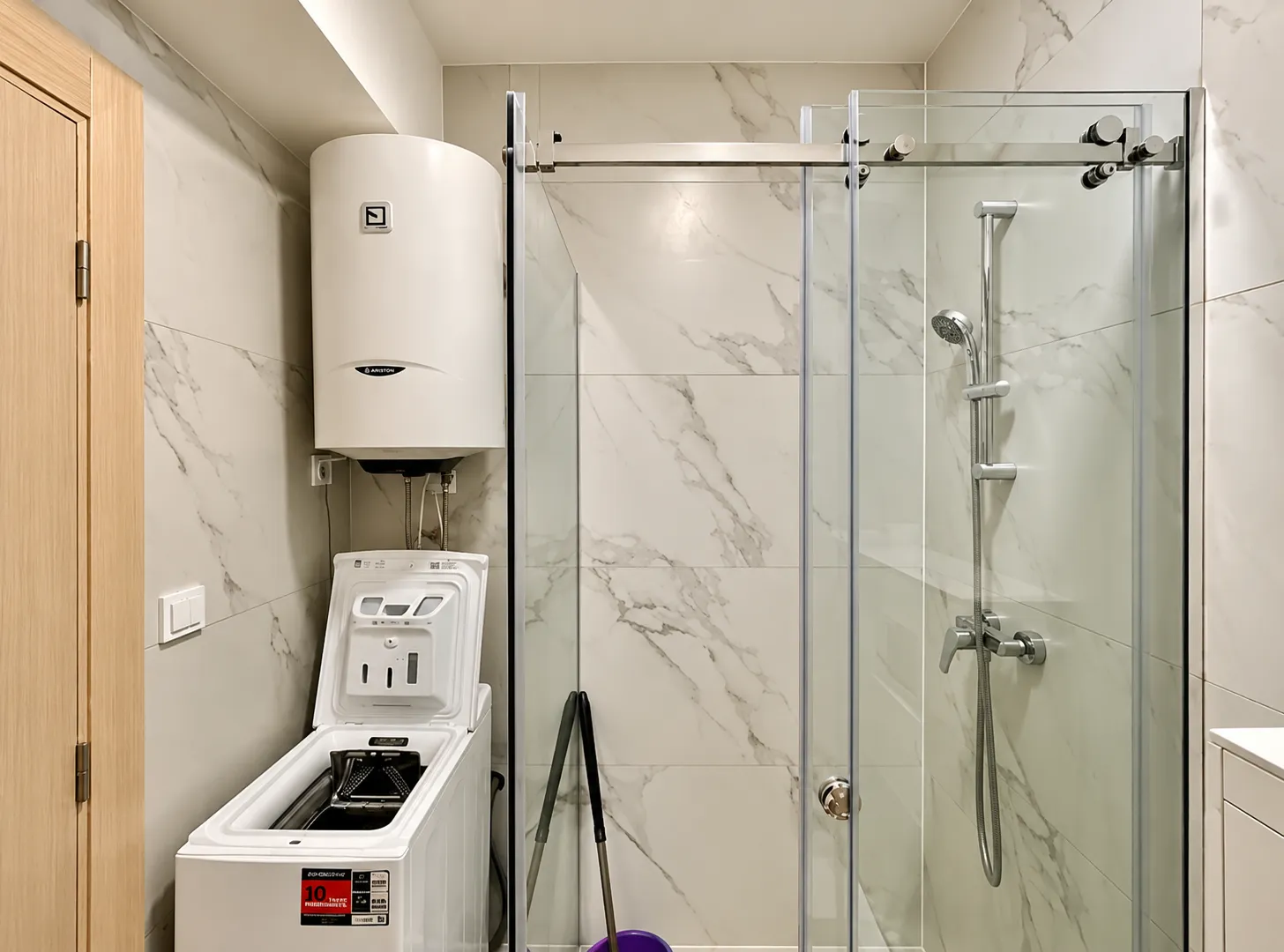 Bathroom with a shower cabin, water heater, and washing machine.