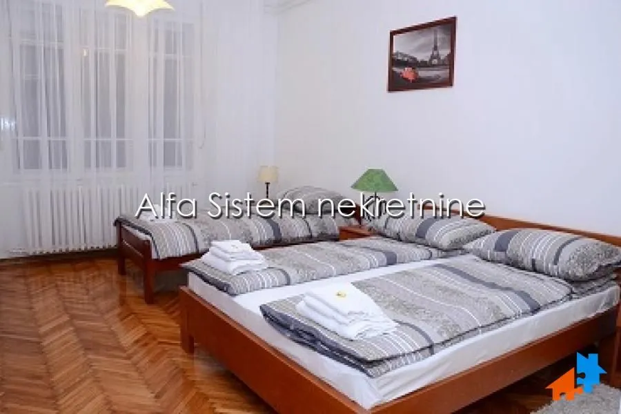 Bedroom with two double beds and wooden flooring.