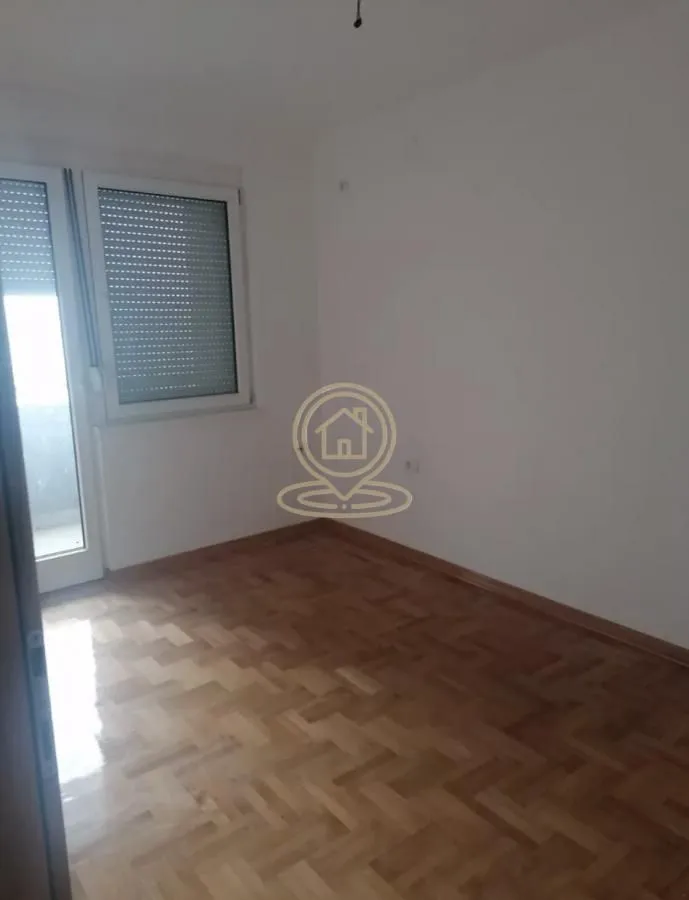 Prazna soba sa parketom i izlazom na terasu.