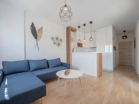 Living room with a sectional sofa, coffee table and an open kitchen in the background. - image 3