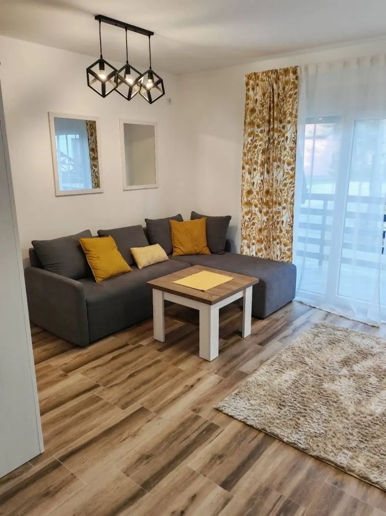 Dnevna soba sa ugaonom garniturom, stočićem i modernim lusterom.