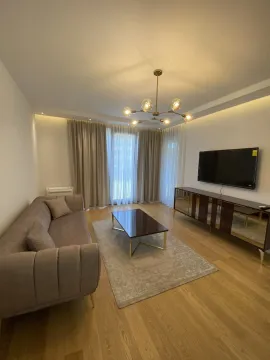 Bright living room with modern furniture, a TV, and an elegant chandelier. - image 10