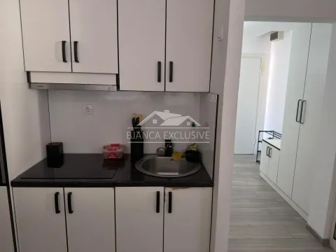 Manja kuhinja sa belim elementima i crnom radnom površinom. - image 3