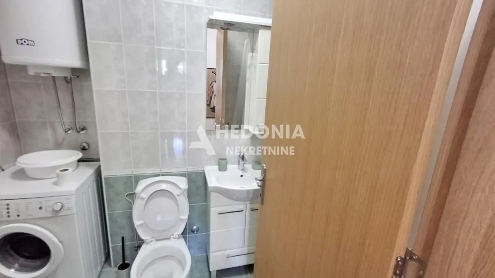 Smaller bathroom equipped with sanitary facilities, a sink, a washing machine, and a water heater.