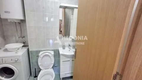 Smaller bathroom equipped with sanitary facilities, a sink, a washing machine, and a water heater. - image 4