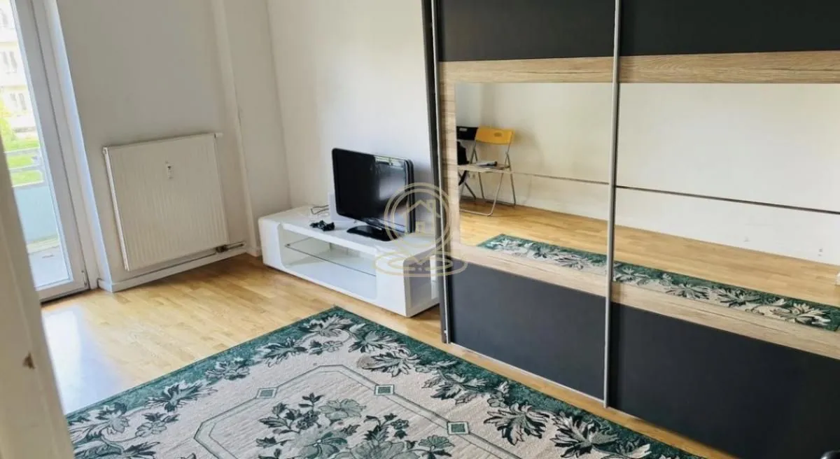 Spavaća soba sa velikim plakarom, TV komodom i tepihom.