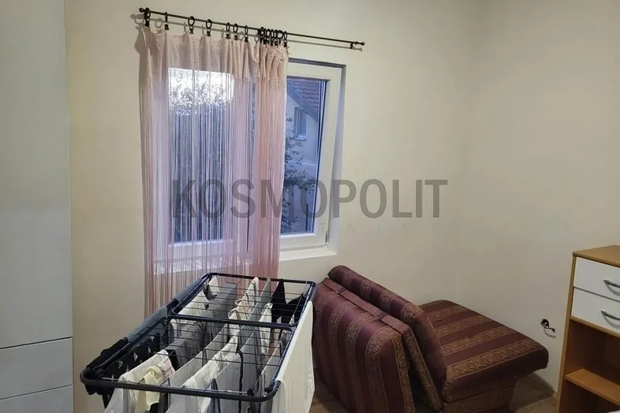 Smaller bedroom with a bed, a drying rack, and a window.