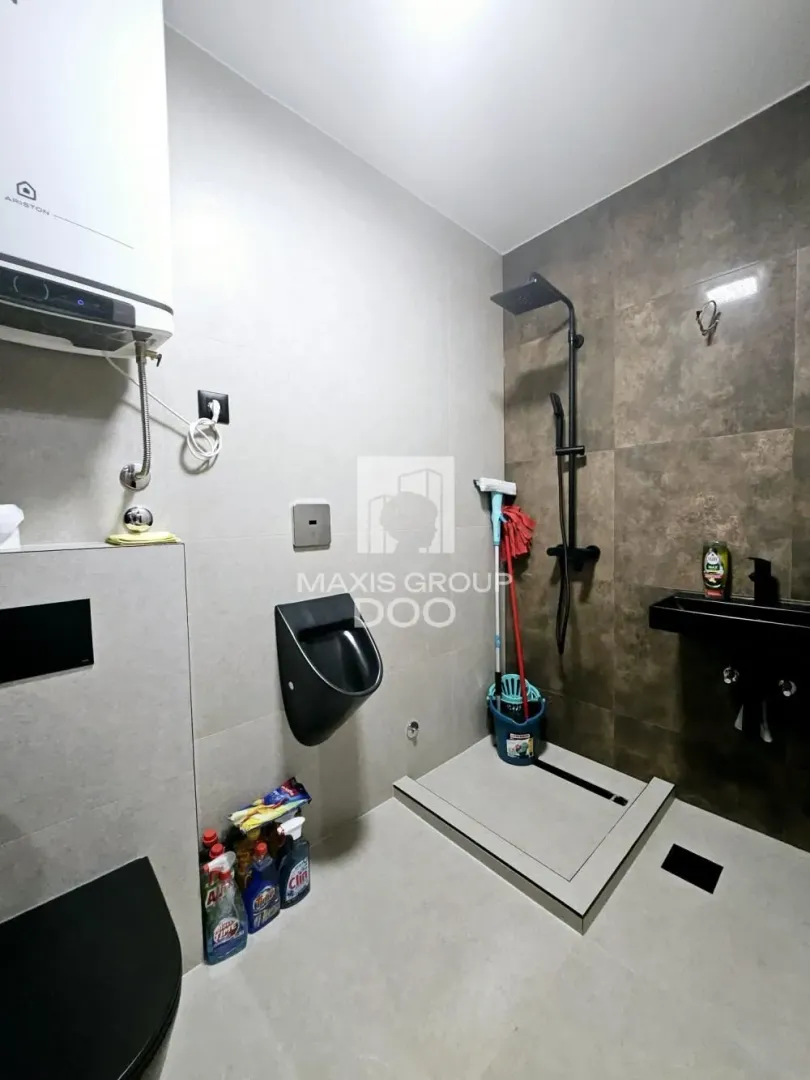 Modern equipped bathroom with a walk-in shower, urinal and water heater.