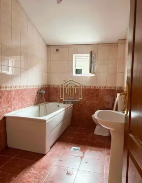 Kupatilo obloženo keramičkim pločicama sa kadom, umivaonikom i toaletom. - image 9