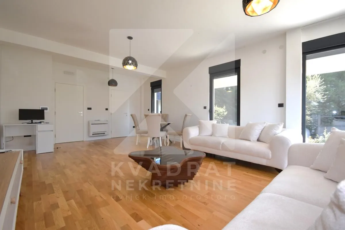 Spacious living room with a sofa set, dining table and hardwood flooring.