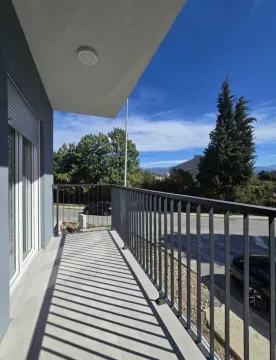 Prostrani natkriveni balkon sa metalnom ogradom i pogledom na ulicu i zelenilo. - image 16