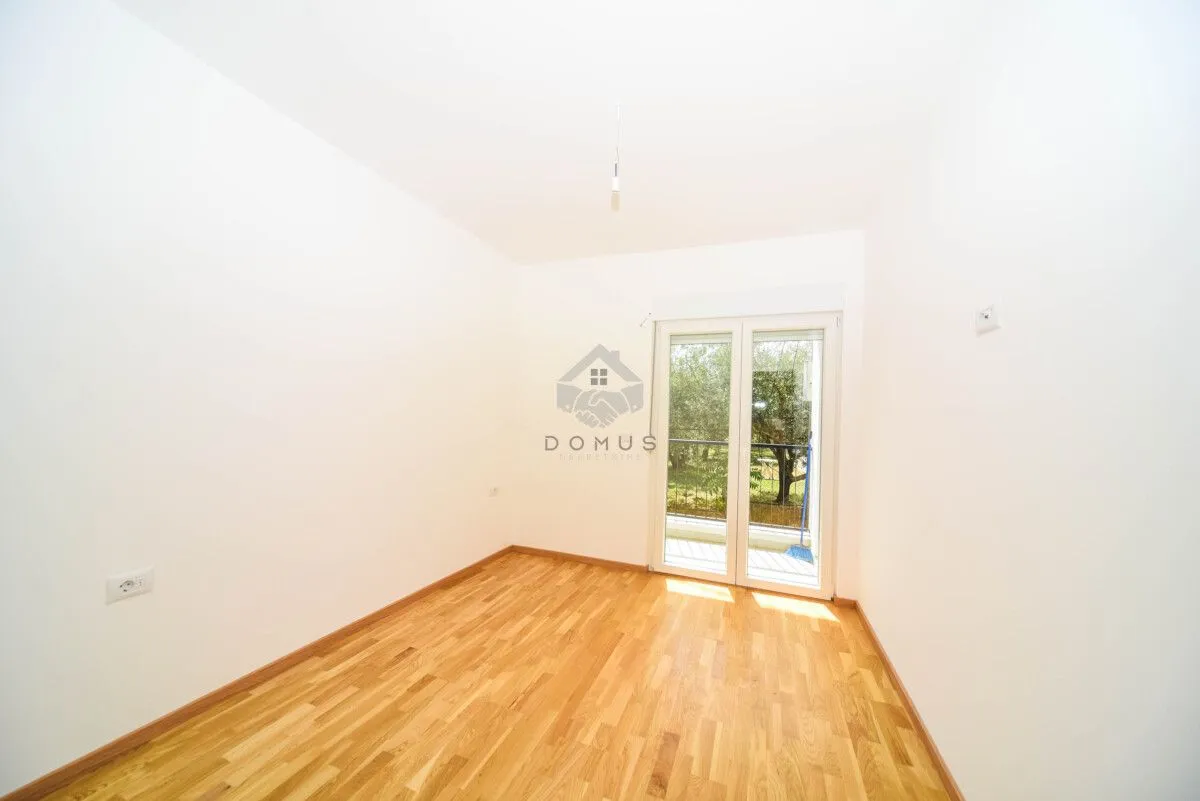 Empty room with hardwood flooring and balcony doors.