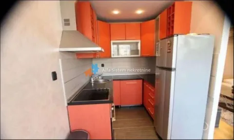Kuhinja opremljena narandžastim elementima i frižiderom. - image 6
