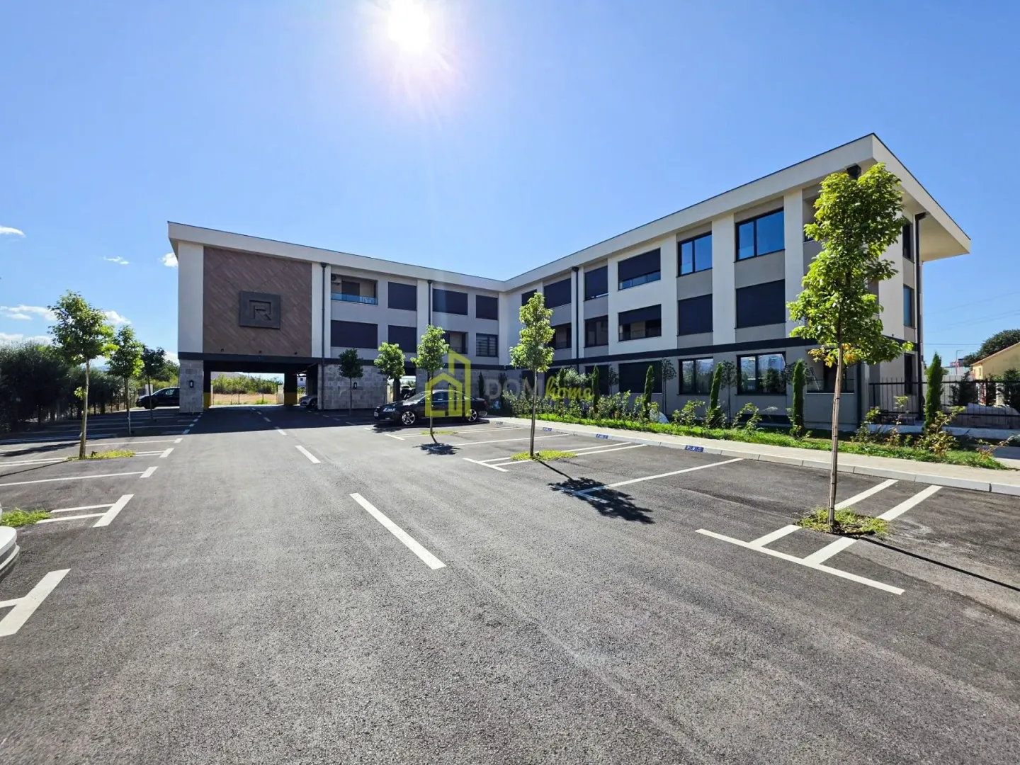 Exterior view of the building with parking space and landscaped greenery.