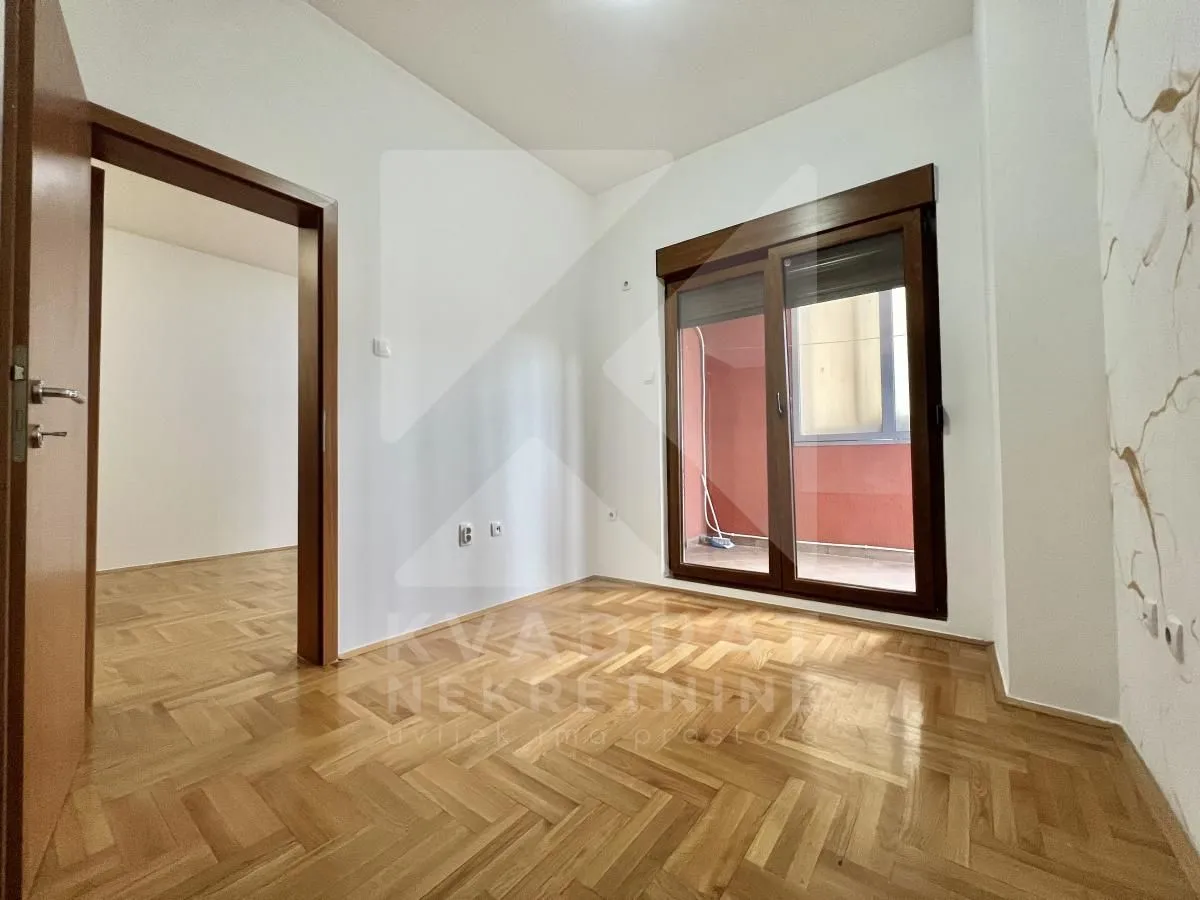 Empty room with parquet flooring and balcony doors.