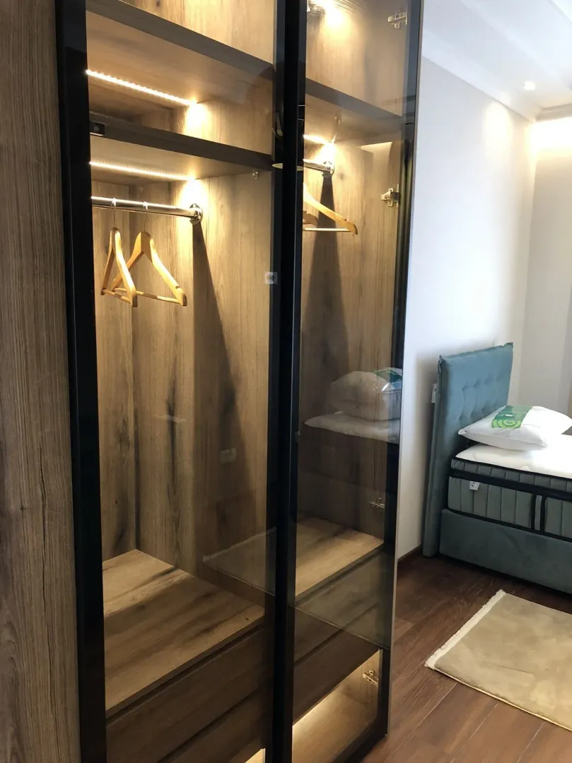 Modern bedroom featuring an illuminated built-in wardrobe next to the bed.