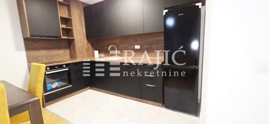 Modern kitchen with dark cabinetry and a dining table.