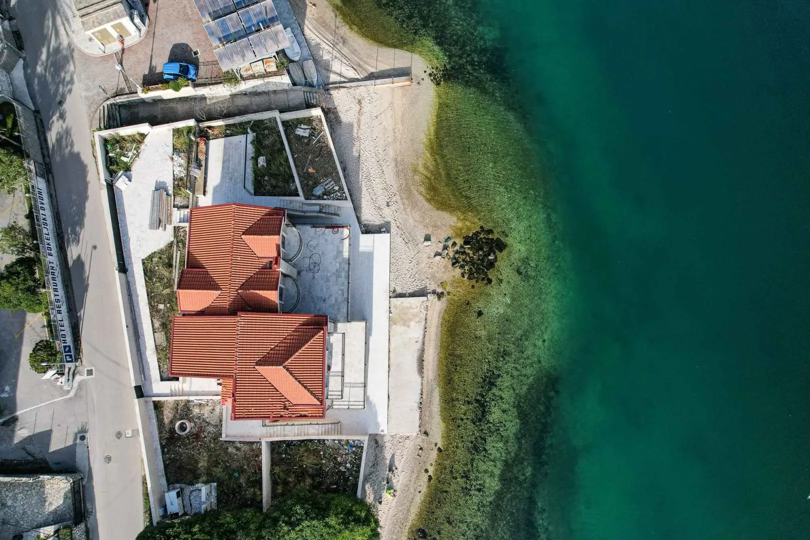 Pogled iz vazduha na kuću sa crvenim krovom pored mora.