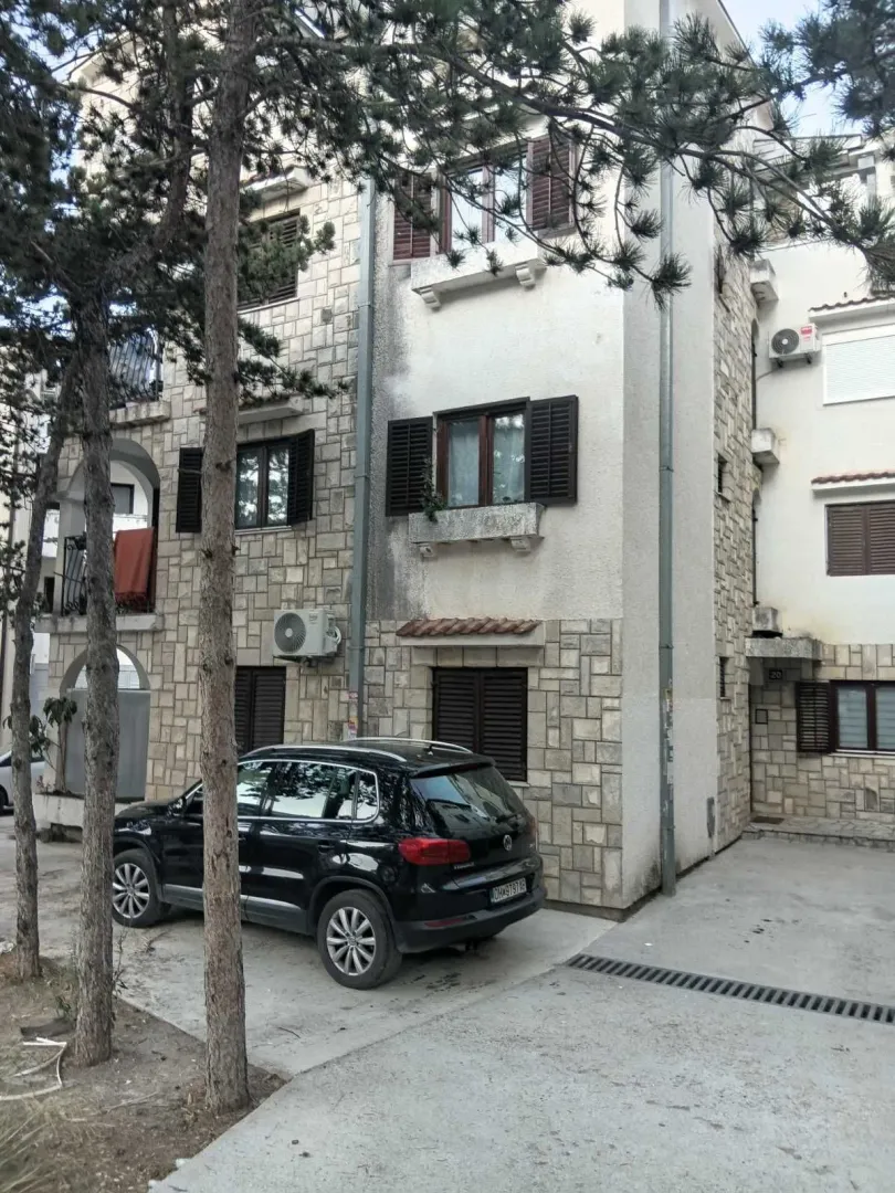 Exterior view of the building with a stone facade and a parked car in the courtyard.