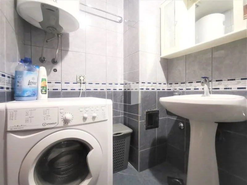 Smaller bathroom with a sink, washing machine, and water heater.