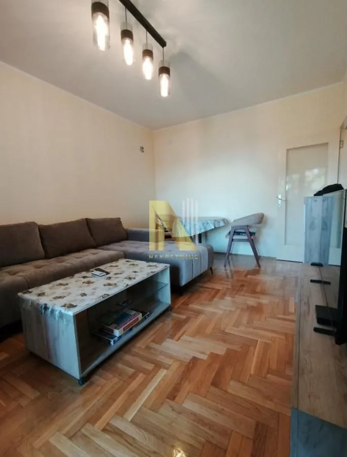 Dnevna soba sa garniturom, stočićem i parketom.