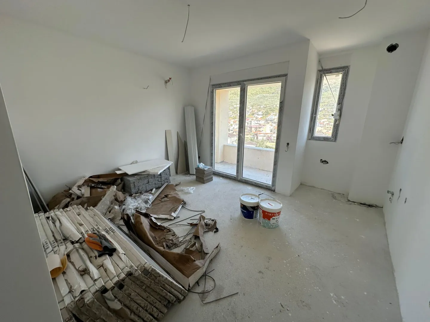 Unfinished room under construction with building materials and access to the terrace.