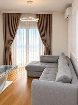 Living room with a grey sectional sofa, coffee table and balcony doors. - image 12