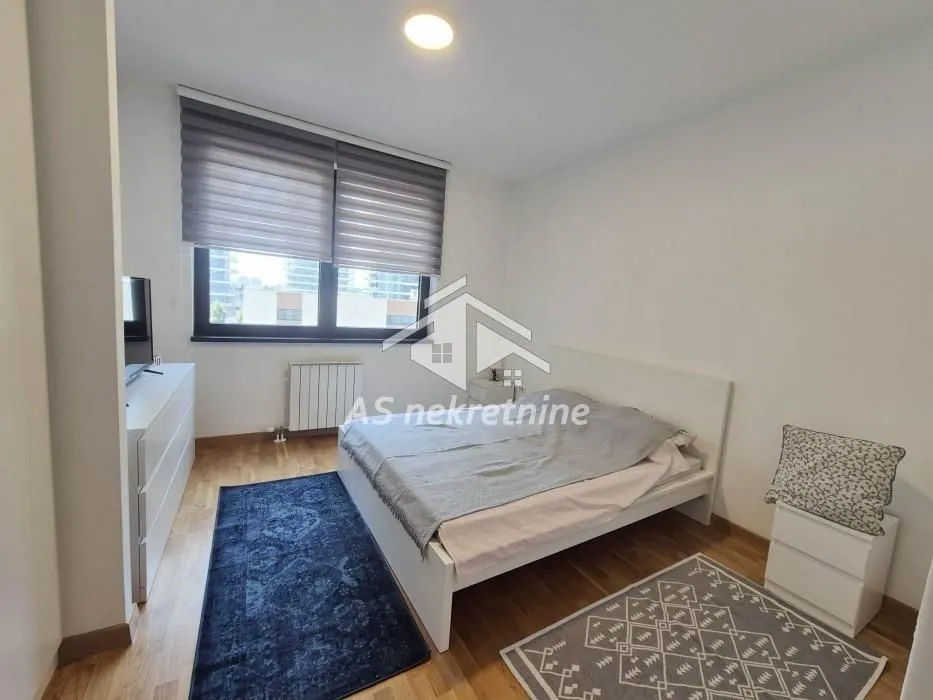 Furnished bedroom with a double bed, window and dresser.