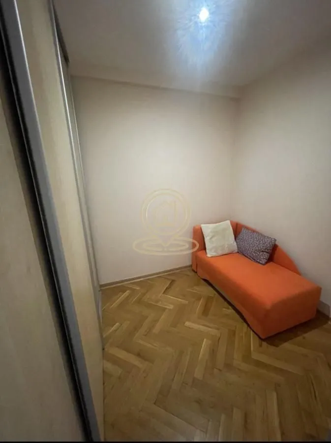 Smaller bedroom with an orange bed and parquet flooring.