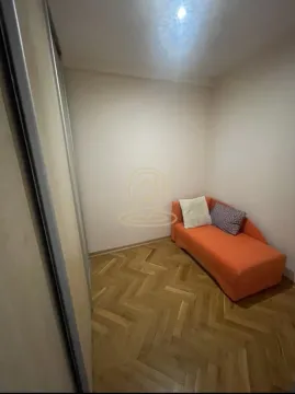 Smaller bedroom with an orange bed and parquet flooring. - image 7