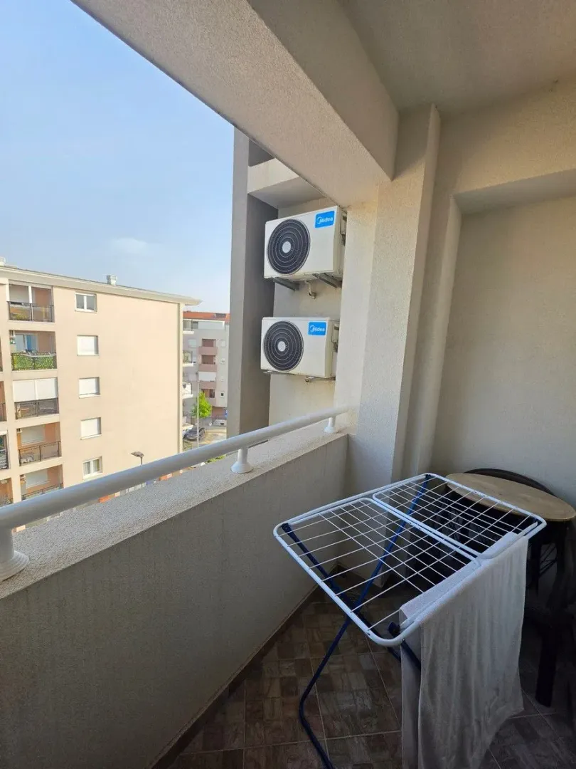 Covered balcony with a drying rack and air conditioning outdoor units.