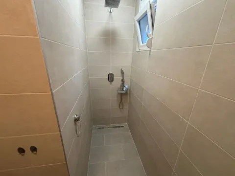 Modern shower cabin lined with beige tiles and a built-in shower faucet. - image 8